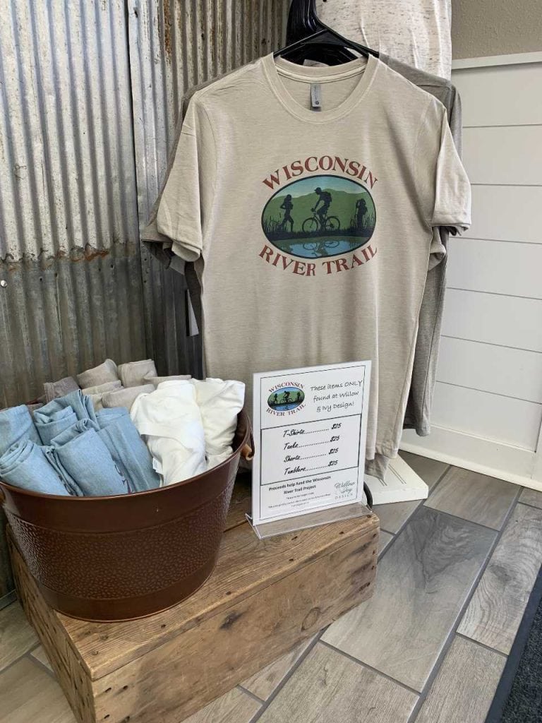 display of Wisconsin River Trail Organization t-shirts for sale in a variety of colors at Willow and Ivy